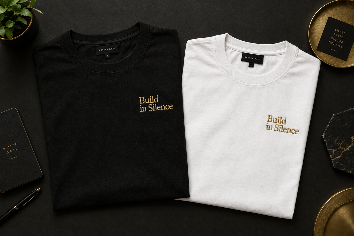 Build in Silence tee — black and white flat lay, gold embroidery